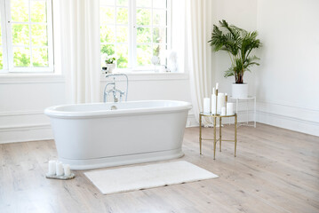 White modern bathroom with silver fittings with large sunny windows, decorations and plants....