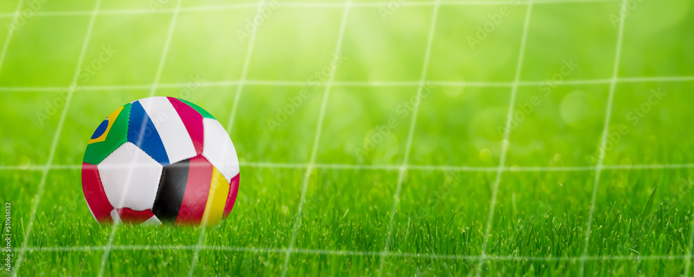 Wall mural closeup of a lying colorful soccer ball in a goal behind net with international flags, symbolic conc