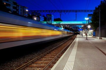 Moving train crosses a railway station in Switzerland