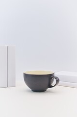 dark blue ceramic bowl and books on the table against white wall