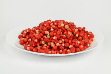 Plate full of wild strawberries, ripe red berries.