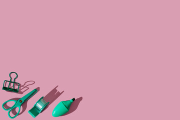 Flat lay pattern composition with school green stationery supplies on pink pastel background. Vivid color minimal overhead shot. Back to school concept. Top view with sharp shadows.