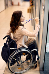 Young businesswoman in wheelchair unlocking her office door with ID card.