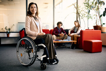 Portrait of happy businesswoman in wheelchair in office looking at camera.