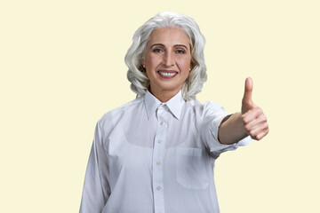 Beautiful smiling senior lady showing thumb up gesture. Isolated on white background.