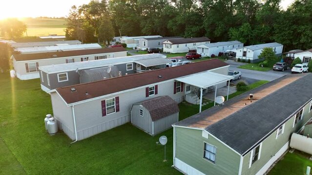 Aerial pull back from mobile home in America. Reveal of beautiful golden hour light over sprawling mobile home park. Low income housing in rural USA.