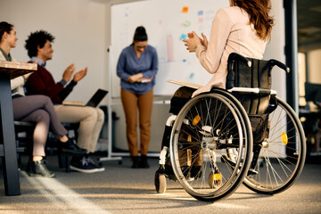 Back view of businesswoman with disability applauding during seminar in board room.
