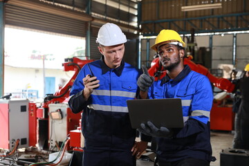 Professional heavy industry technician engineer maintenance and check part of robot arm machine in intelligent factory with computer and walkie talkie. Industrial and technology support system concept