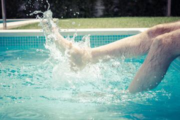 legs of man splashing in the pool on a hot summer day
