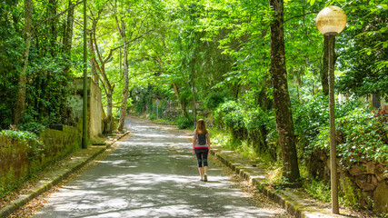 Girl walking in San Leonardo forest under tall green trees