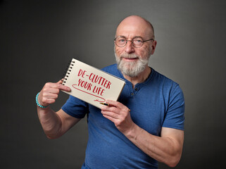 declutter your life - senior man (in late 60s) showing notebook with an inspirational note, healthy...