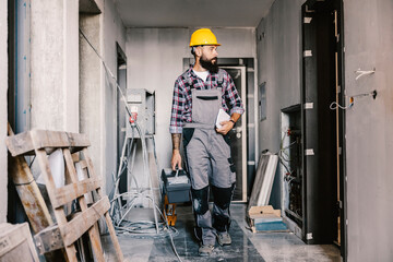 A worker with toolbox arrives at his workplace, unfinished building.