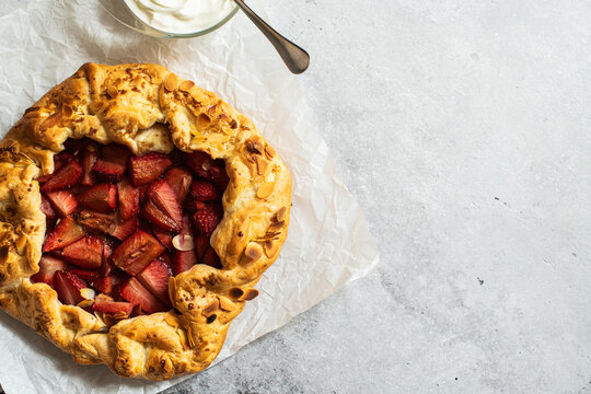 Strawberry summer galette with puf pastry and almond flakes on gray background. Copy space.