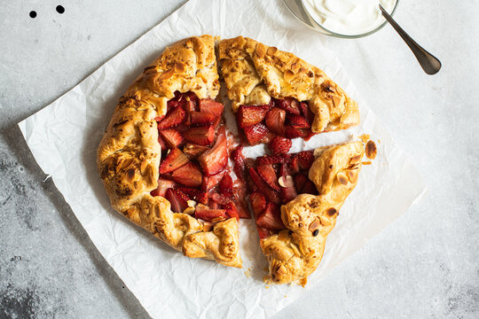Strawberry summer galette with puf pastry and almond flakes with cream. Top view.