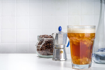 Fizzy coffee drink. Coffee espresso with carbonated mineral water and crushed ice, with coffee maker, milk roasted coffee beans on white background copy space