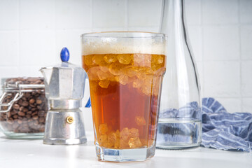 Fizzy coffee drink. Coffee espresso with carbonated mineral water and crushed ice, with coffee maker, milk roasted coffee beans on white background copy space