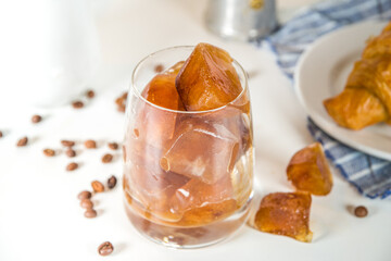Cold coffee cocktail with frozen coffee espresso ice cubes and milk. Summer cool refreshment latte drink on white background copy space