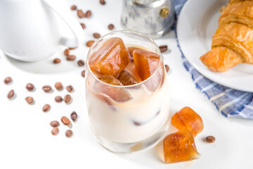 Cold coffee cocktail with frozen coffee espresso ice cubes and milk. Summer cool refreshment latte drink on white background copy space