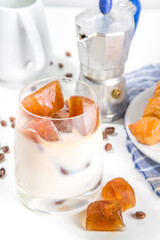 Cold coffee cocktail with frozen coffee espresso ice cubes and milk. Summer cool refreshment latte drink on white background copy space