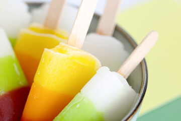 Close up colorful Homemade fruit ice cream bar pop stick in a bowl  isolated on colorful pastel background, top view copy space. Refreshing snack for children in the summer. 