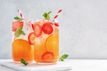 Delicious Orange lemonade with strawberries on grey table, space for text. Fresh summer cocktail