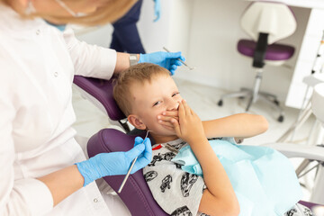 Dentist examining little boy's teeth in clinic