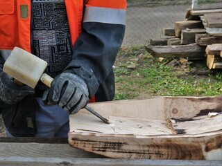 woodworking with a mallet and chisel, gouging a niche in a piece of wood for use in panning for gold, hands of a village carpenter in the process of working with hand tools