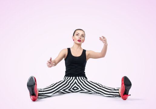 Young woman doll in stripe pants with arms outstretched sitting on the floor fashion style glamor. On light pink background.