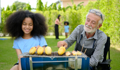 Family holiday activities with grandfather, mother and children with camping. bbq grill and play in...
