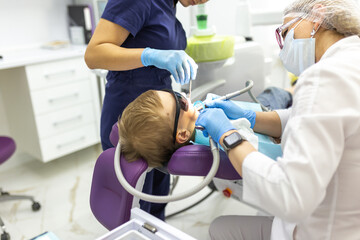 Obraz premium Close-up dentist procedure of kids teeth. A child boy with a dentist in a dental office