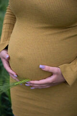 Pregnant woman with big late pregnancy time tummy holds her stomach