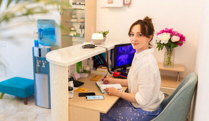 Woman Receptionist. Reception Workplace. Workplace in Beauty Salon. White Interior. White Reception Desk. Beauty Consept