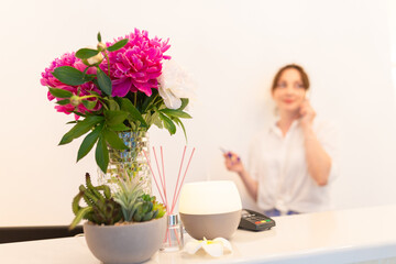 Blur background. Beautiful woman talking on phone at reception desk in beauty salon