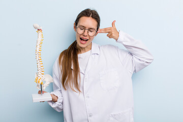 young adult woman looking unhappy and stressed, suicide gesture making gun sign. spine specialist...