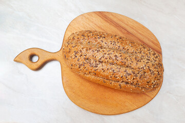 White bread with seeds on a wooden cutting board. Top view.