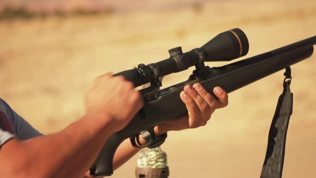 Close-up of loading rifle with scope in the heat in a desert in America