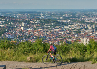 Nice active senior woman with electric mountain bike on a tour in the hills above the city of...
