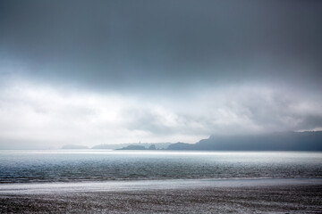 Dramatic stormy day with a hazy layered coastal landscape, viewed across the sea to Tenby Wales