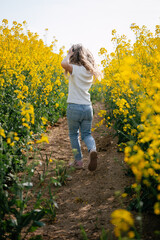Naklejka na ściany i meble Young girl child runs through the summer yellow field back photo