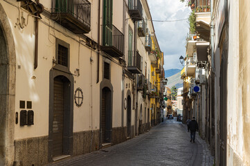 Narrow historic (medieval) streets of a small town in southern Italy. Old stone houses, wooden windows and doors, cobblestone road.