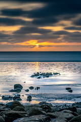 Fototapeta na wymiar Sunset of the sea with rocks and clouds in the background. Beach and sea water with long exposure.