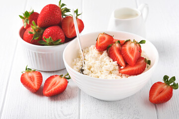 Cottage cheese with strawberries. Breakfast from cottage cheese with slices fresh strawberries, cream, cup of coffee in white bowl on white wooden background. Top view. Food concept. Mock up.