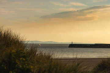 Sunset on the beach with breakwaters and a lighthouse