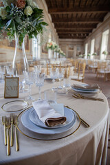 Hall of an ancient castle with catering for wedding events. The tables are set up with fine plates, glasses and cutlery