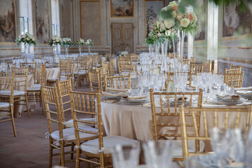 Hall of an ancient castle with catering for wedding events. The tables are set up with fine plates, glasses and cutlery