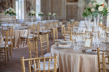 Hall of an ancient castle with catering for wedding events. The tables are set up with fine plates, glasses and cutlery
