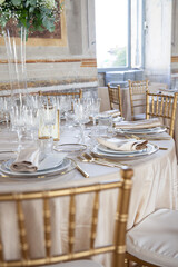 Hall of an ancient castle with catering for wedding events. The tables are set up with fine plates, glasses and cutlery