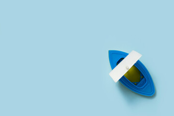 Plastic toy boat on a blue background. Top view, flat lay