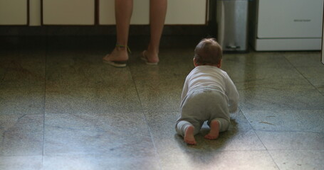 Cute baby infant crawling on kitchen floor home