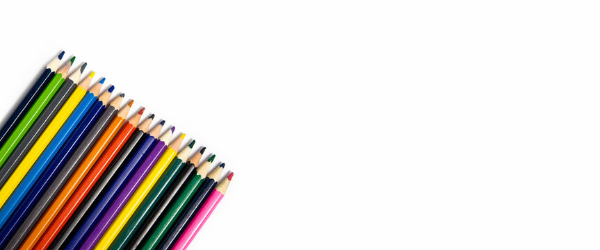 Many multi-colored pencils on a white background. Top view, flat lay. Banner.